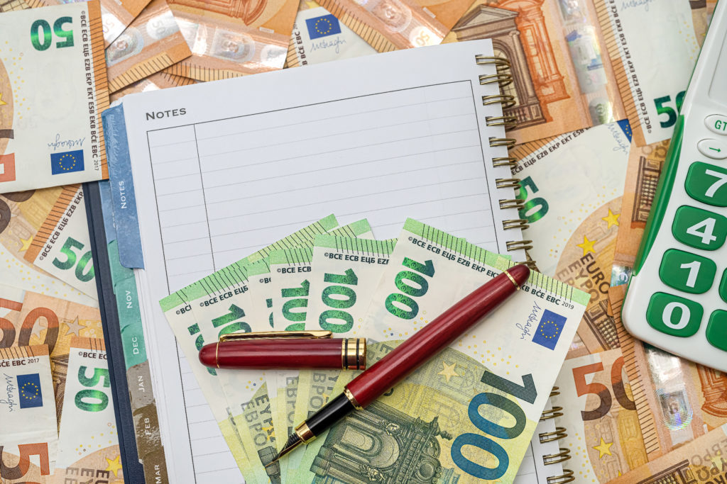 Calculator keyboard green clean new notepad and red pen stand on new euro banknotes. Business money concept